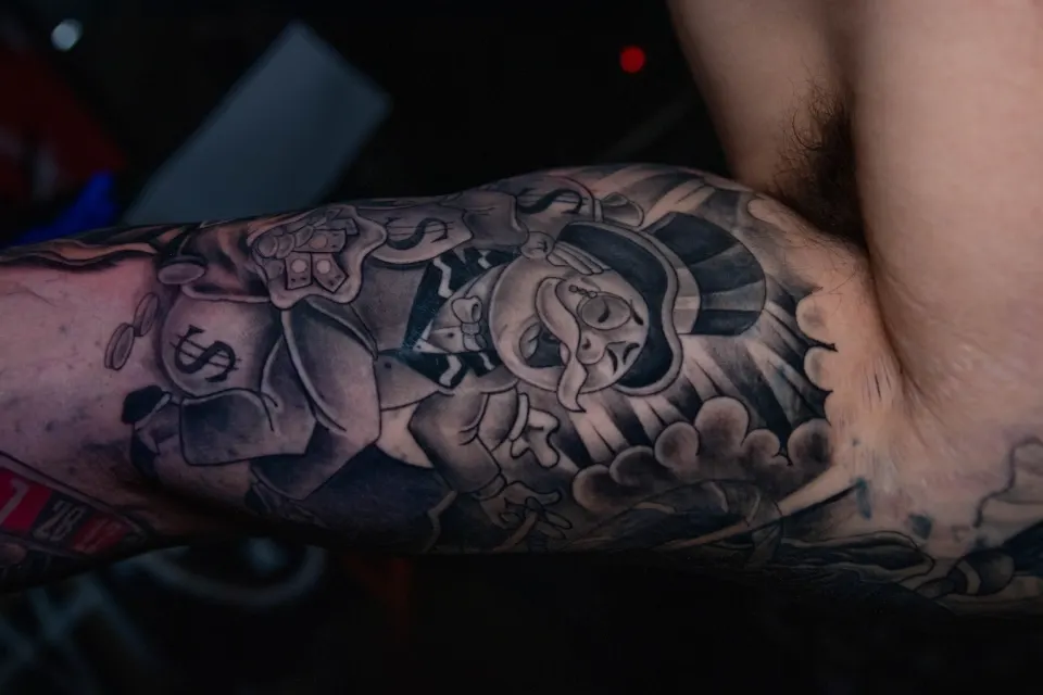 Black and grey calf tattoo of an Aztec deity carved in stone-relief style