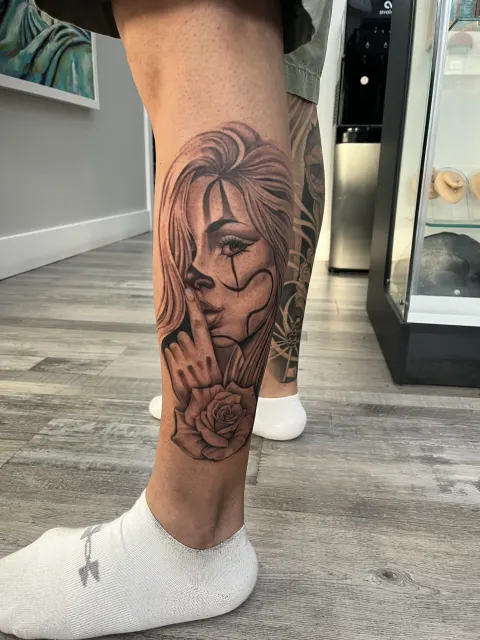 Black and grey calf tattoo of a clown girl in chicano style