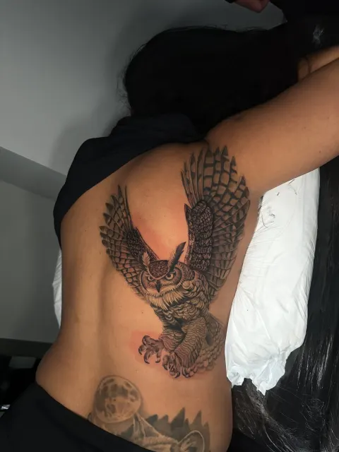 Black and grey rib tattoo of an eagle descending with talons open