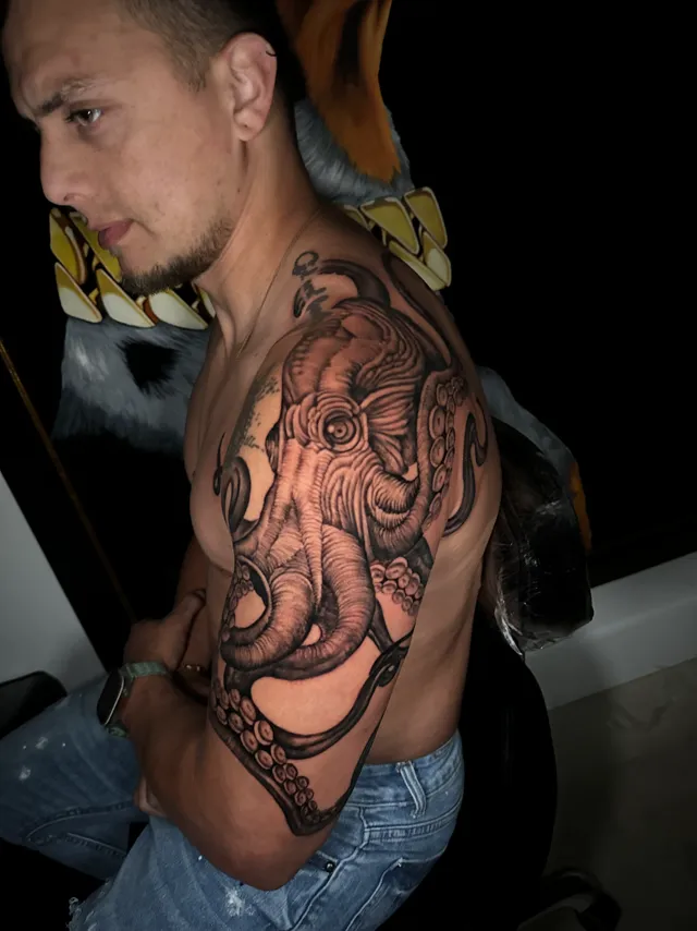 Black and grey shoulder tattoo of an elephant with a curling trunk