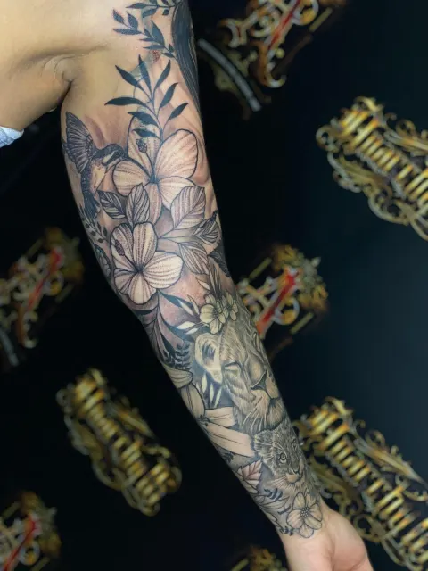 Fine-line sleeve of jasmine blossoms and leaves running down the arm