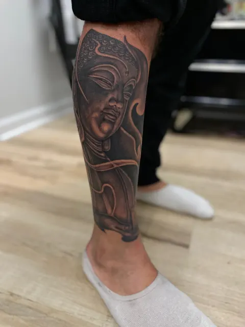 Black and grey hannya mask tattooed down the calf, worked entirely in shades of grey