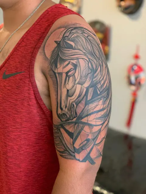 Black and grey shoulder tattoo of a horse in flowing linework