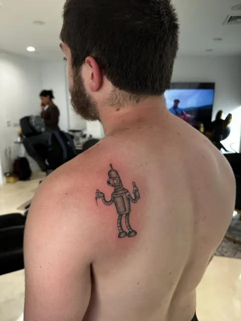 Small black and grey shoulder tattoo of a walking devil with a trident