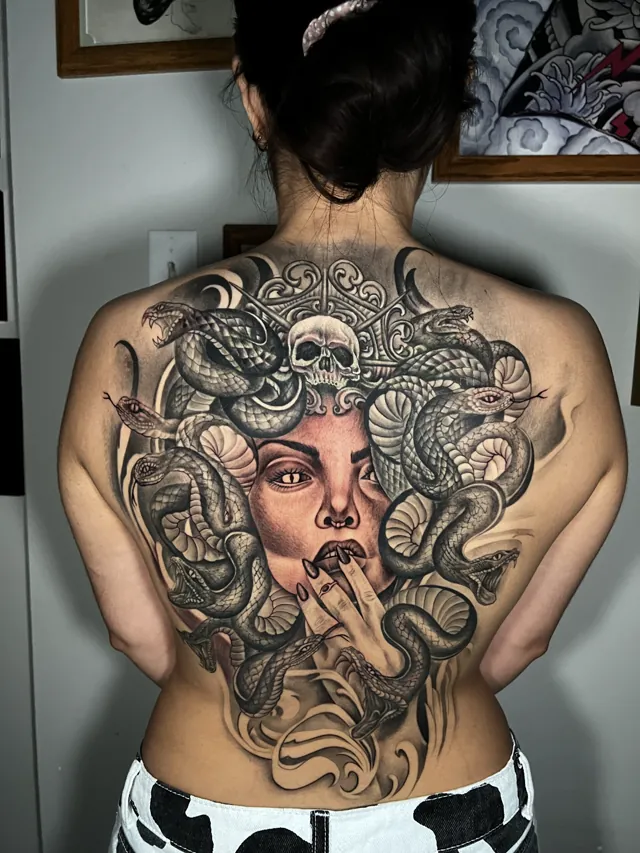 Large black and grey Medusa tattoo composed across the upper back