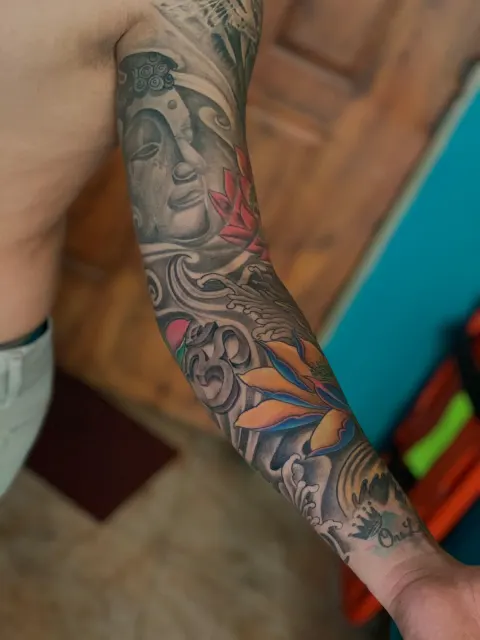 Black and grey full sleeve joining a woman's portrait with skulls and rolling waves