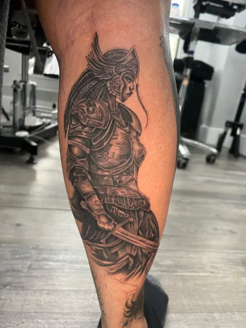 Black and grey calf tattoo of an armored samurai standing with a katana