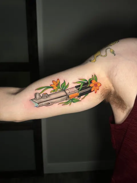 Inner-arm color tattoo of a blade wrapped in orange blossoms