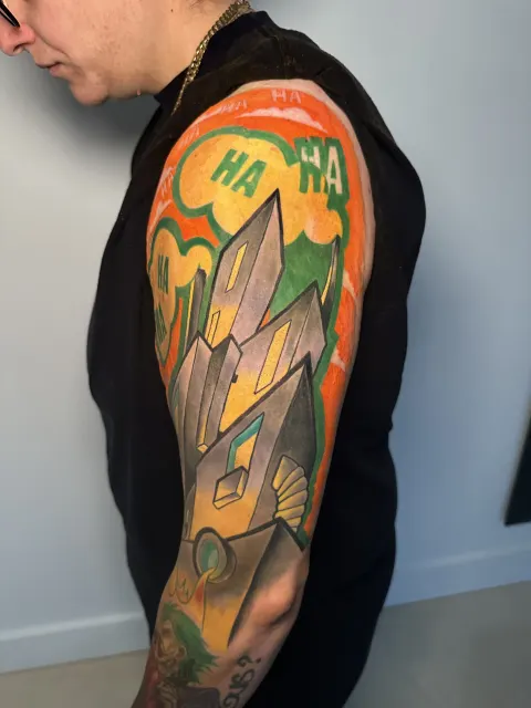 Color upper-arm tattoo of a crystal formation over an orange spray-paint backdrop