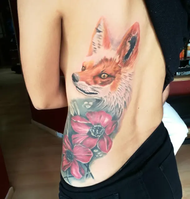 Color rib tattoo of a fox walking through pink poppies