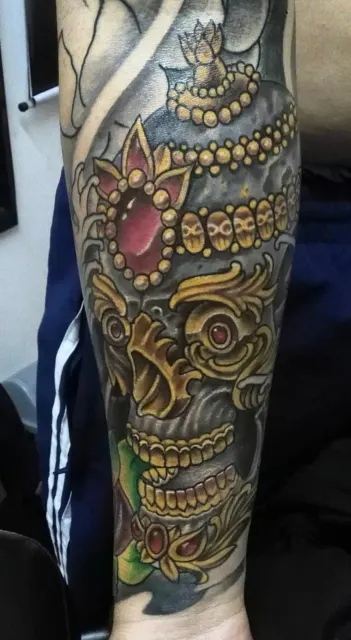 Forearm tattoo of an ornamental skull crusted with gold filigree and red jewels