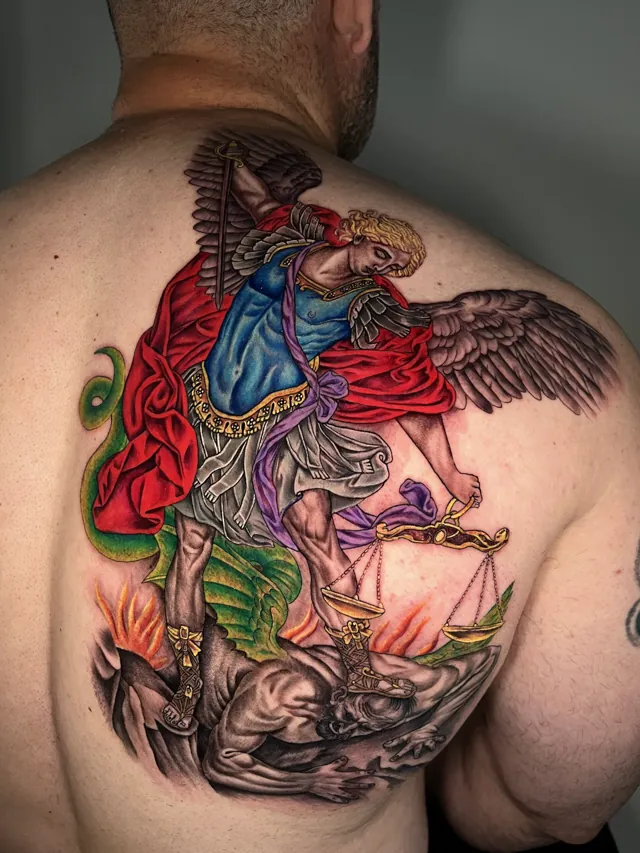 Large color back tattoo of Saint Michael with wings, a sword and scales, standing above a horned figure