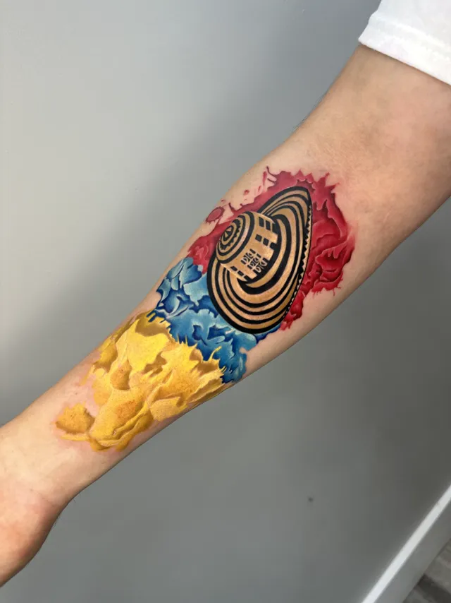 Color forearm tattoo of a Colombian sombrero vueltiao over yellow, blue, and red tones