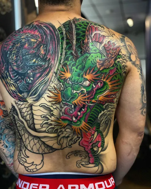Full-back neo-oriental tattoo of a green dragon descending through storm clouds