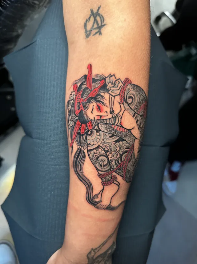 Neo-Oriental forearm tattoo of an armored figure with red accents