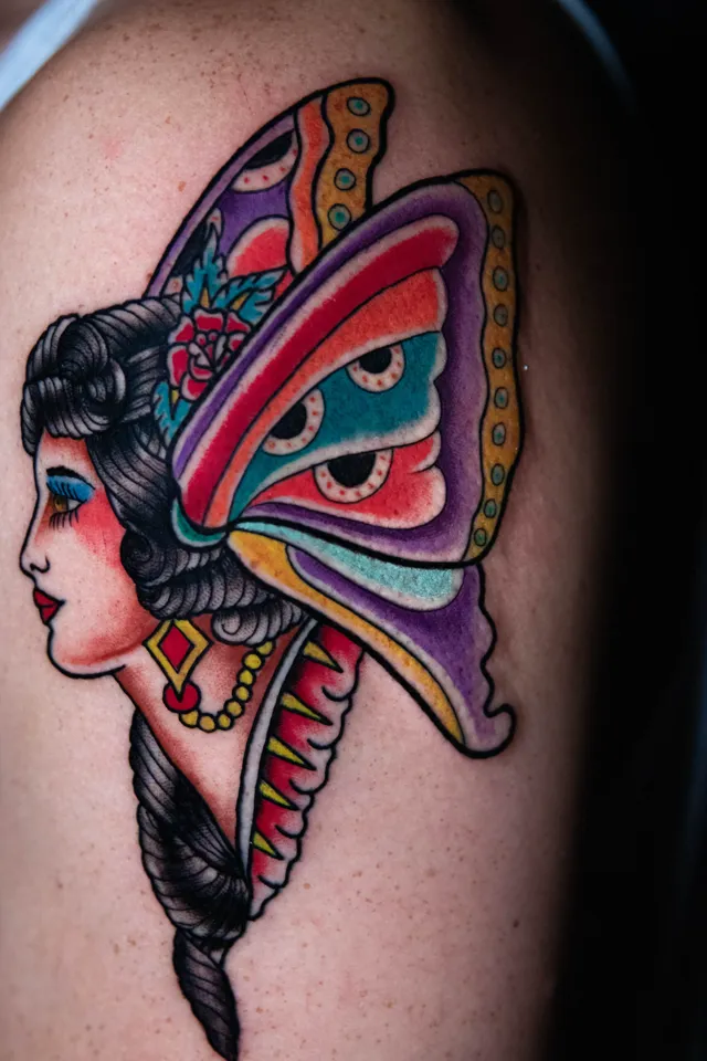 Traditional upper-arm tattoo of a woman's profile framed by butterfly wings