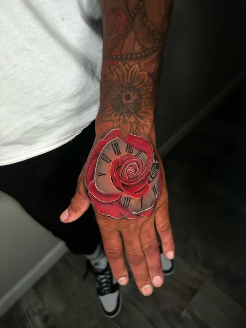 Traditional red rose tattooed across the back of the hand
