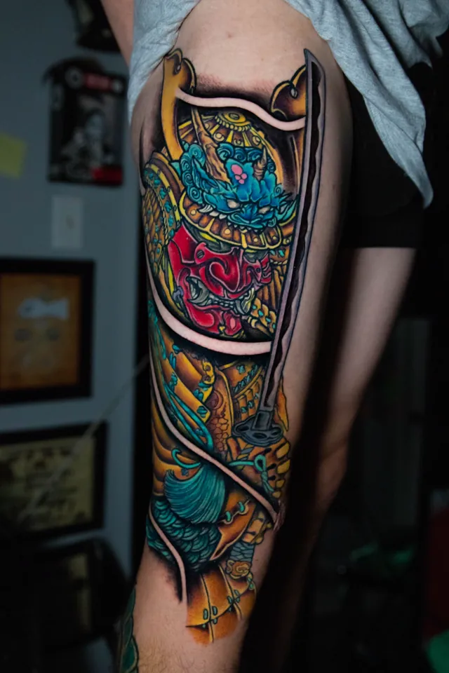 Bold traditional tattoo of samurai armor in black, red, gold, and green